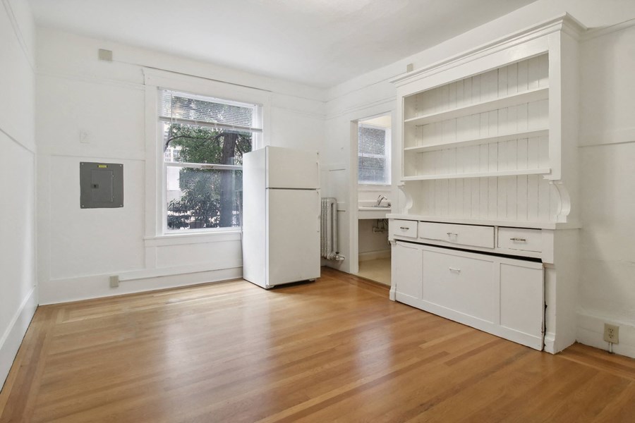 a kitchen with white cabinets and a window and a wood floor